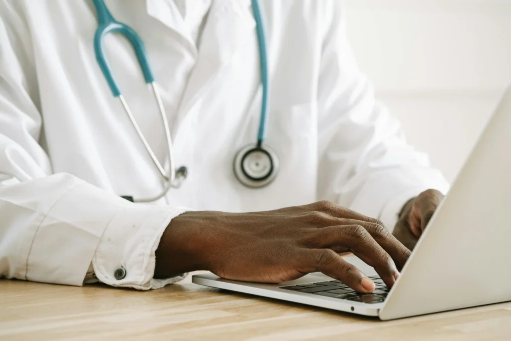 Healthcare professional working on a computer while researching treatment plans from the best TRT online clinics.