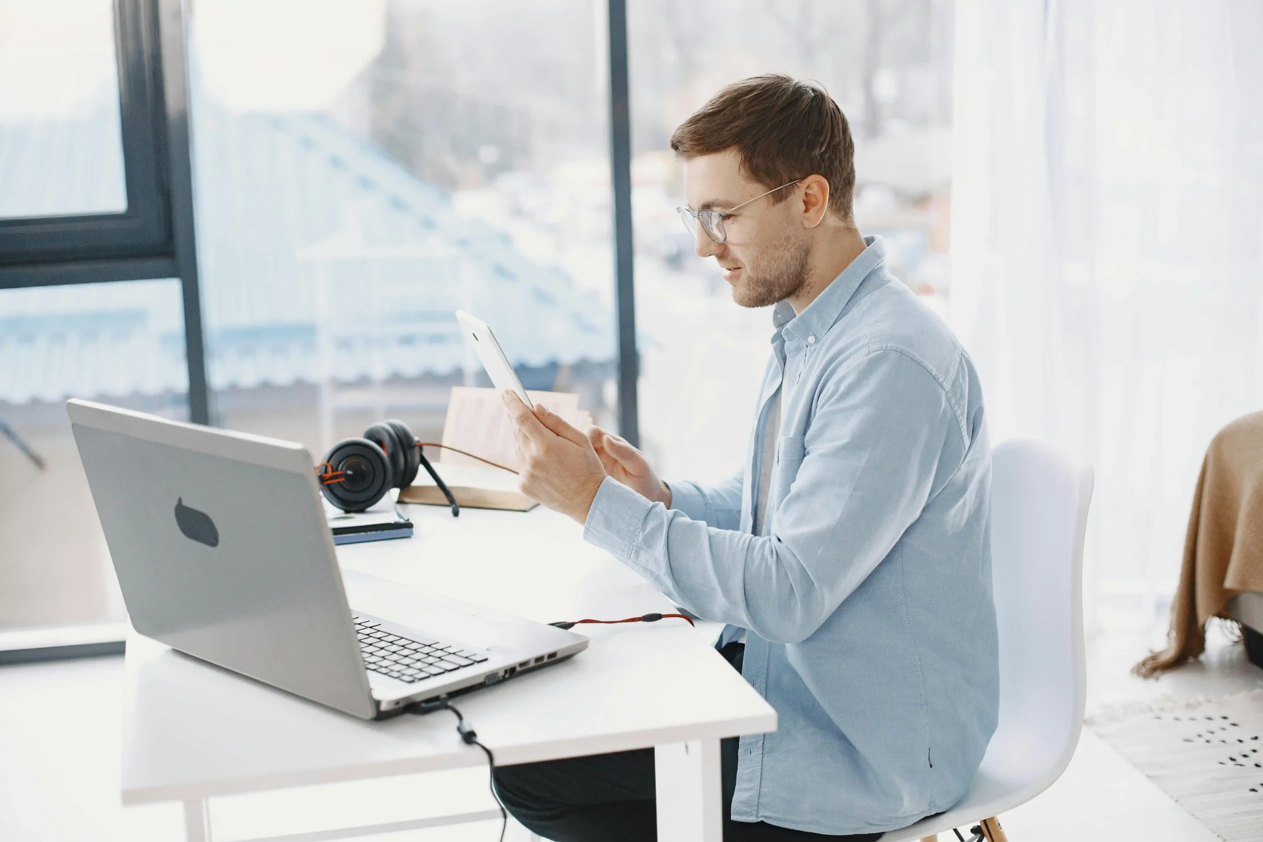 Man researching the cheapest TRT online on his phone and laptop at a home desk.