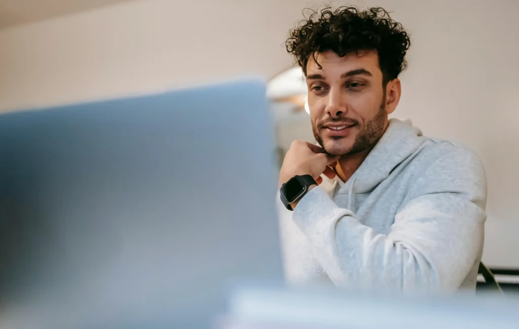 Man using a laptop at home while researching testosterone replacement therapy options and wellness information.