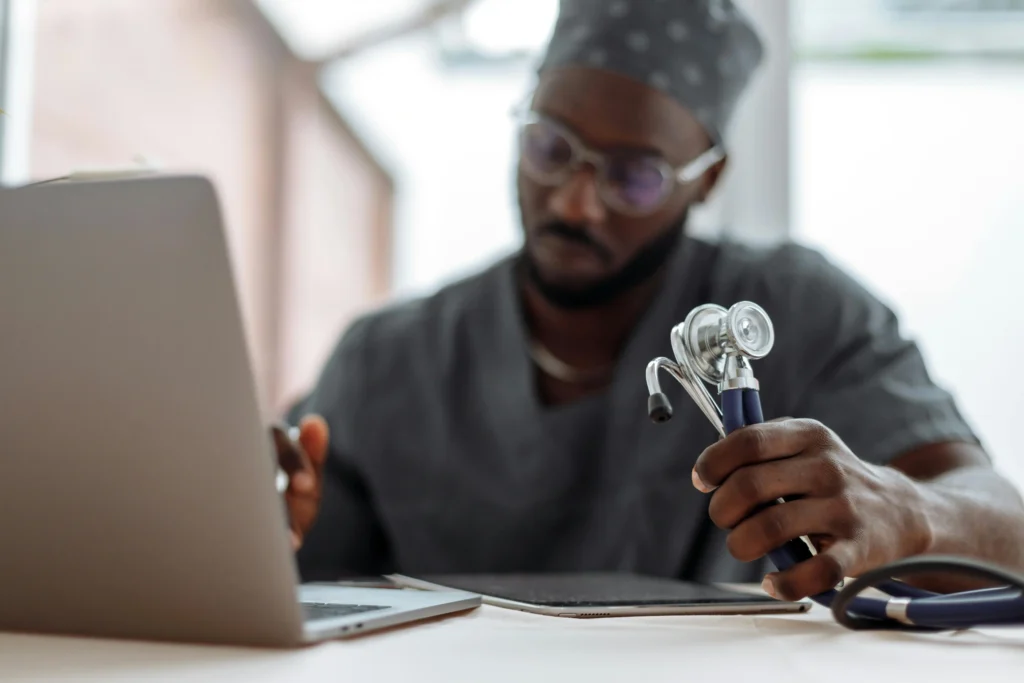 A focused healthcare professional reviews medical data on a laptop while holding a stethoscope, analyzing the various clinical causes of low testosterone to determine an accurate diagnosis for a patient.