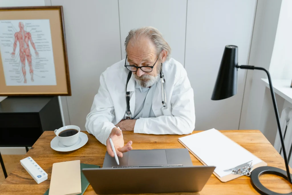 Doctor conducting a virtual consultation at a desk while explaining how to get TRT online through a telehealth appointment.