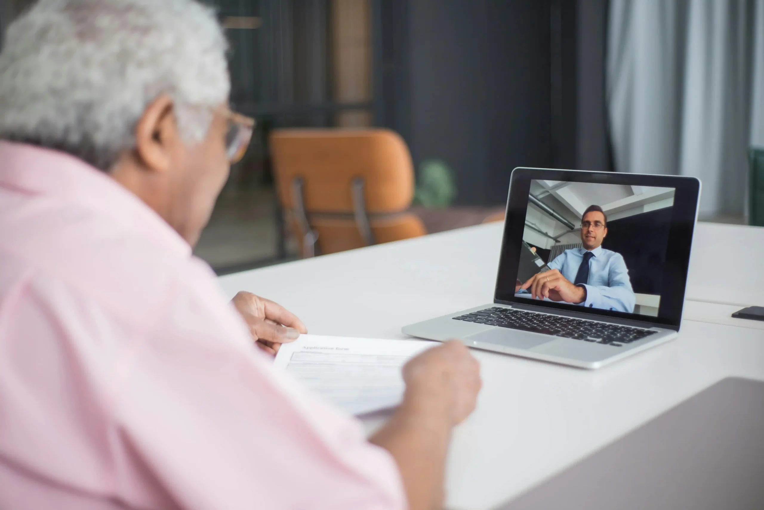Man at his desk reviewing a telehealth video consultation on a laptop, illustrating how to get TRT online through a virtual provider visit.