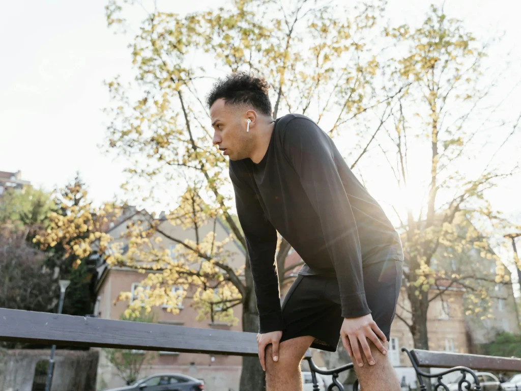 Man in black athletic wear resting after an outdoor workout, illustrating TRT results related to stamina, energy, and physical performance.