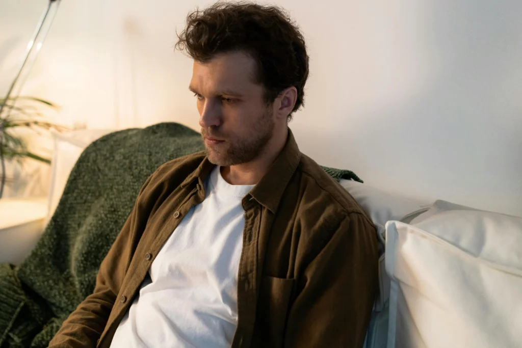 Man in casual clothing at home, thinking about the mistakes he made while managing his TRT dosage.
