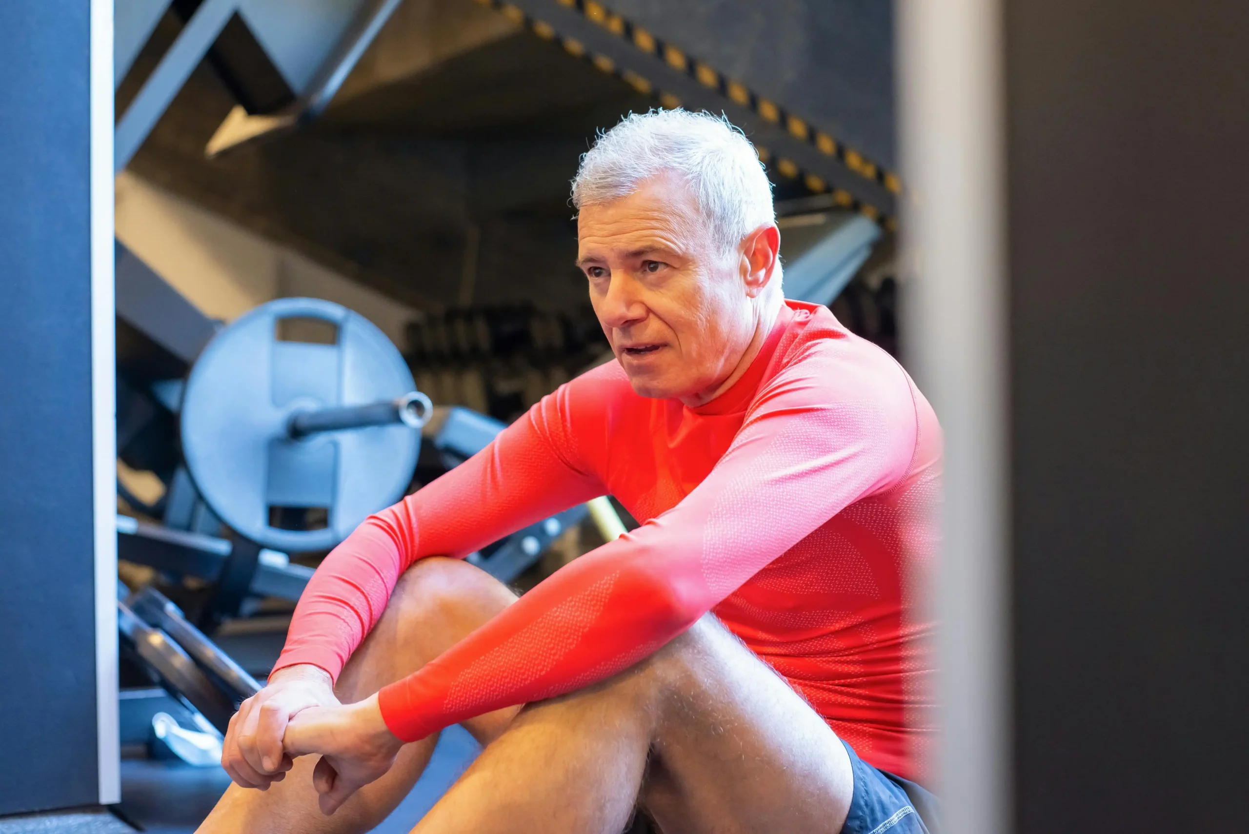 Middle-aged man in workout clothes pausing during exercise, illustrating the kind of fatigue and motivation issues men hope TRT results will address.