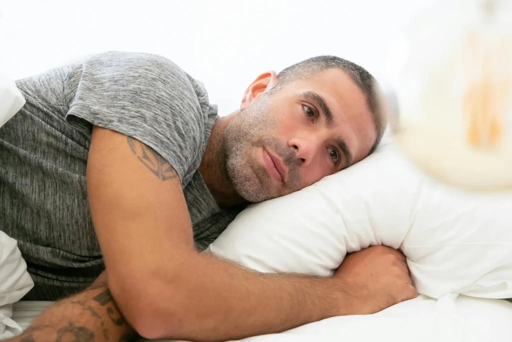 Man lying awake in bed with a worried expression, representing concerns about TRT and fertility and how hormone therapy may affect reproductive health.