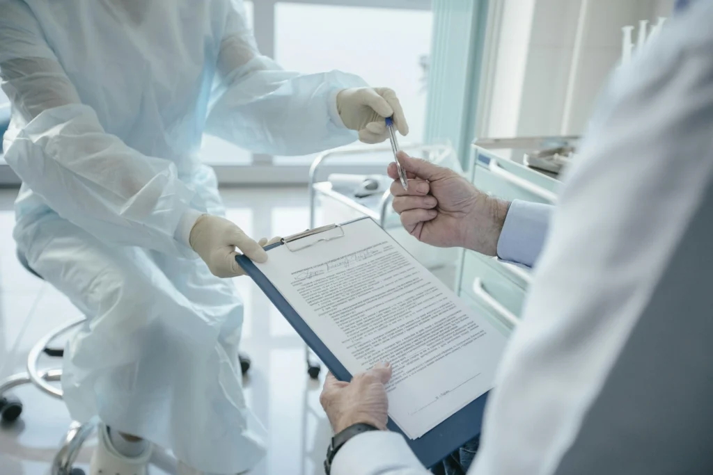 Patient signing medical forms in a clinical setting to confirm if TRT is covered by insurance for their specific treatment plan.