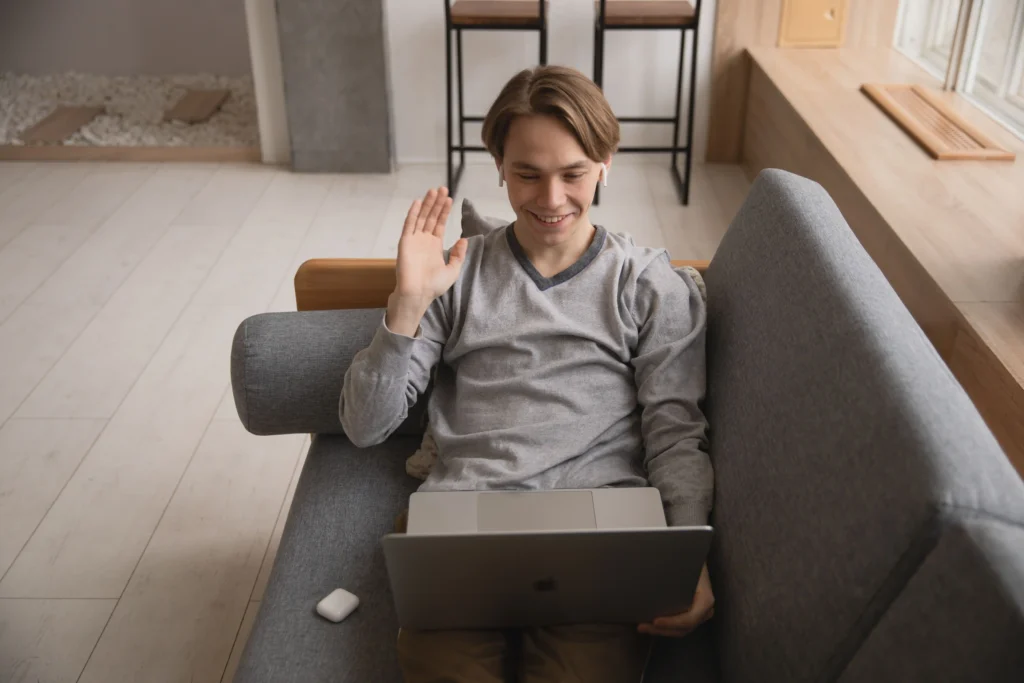 Young man participating in an online telehealth consultation from home, discussing ED treatment options with a healthcare professional on a laptop.