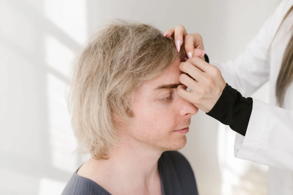 Healthcare professional examining a man’s hairline during a hair loss consultation, representing discussions about finasteride side effects, treatment considerations, and male pattern baldness management.