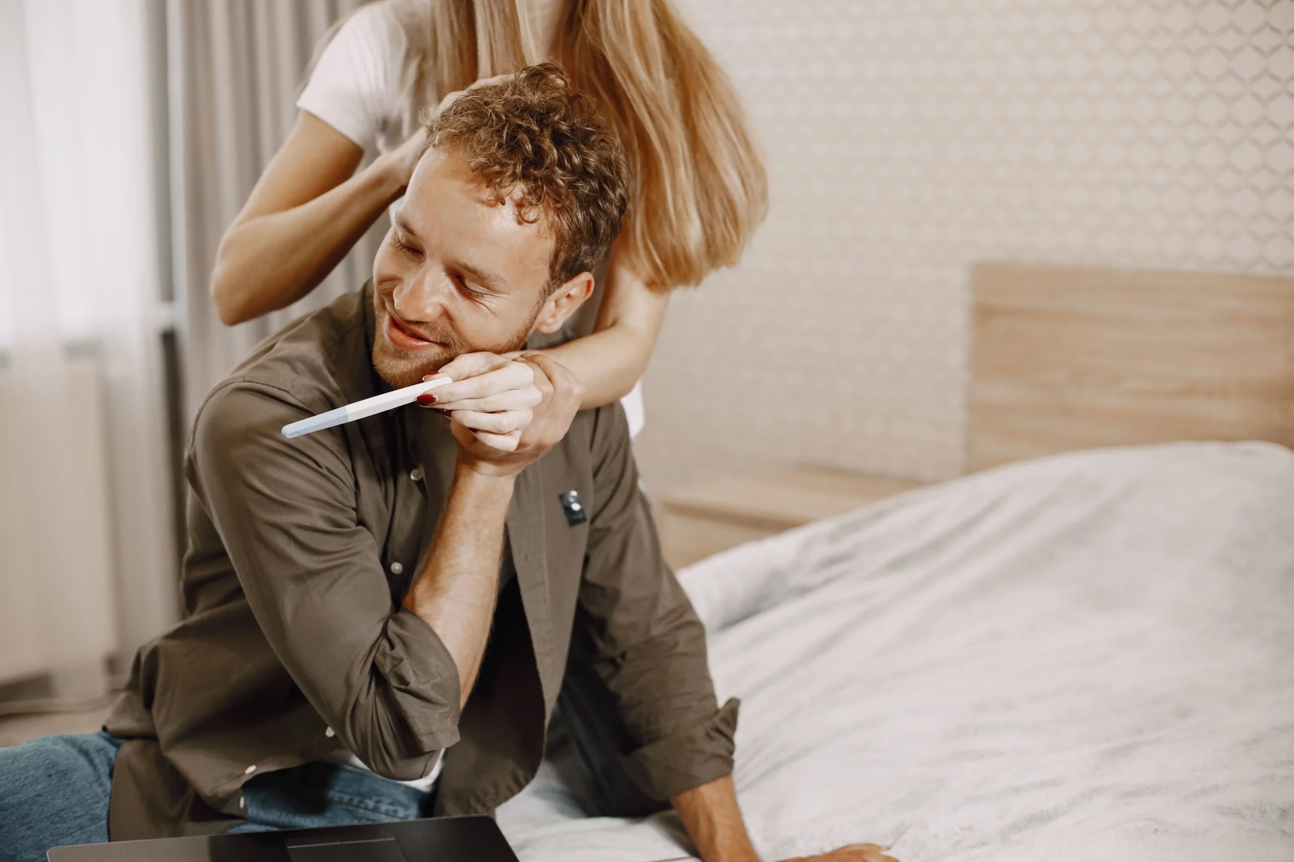 Couple embracing while holding a pregnancy test, depicting the potential fertility benefits associated with HCG TRT.