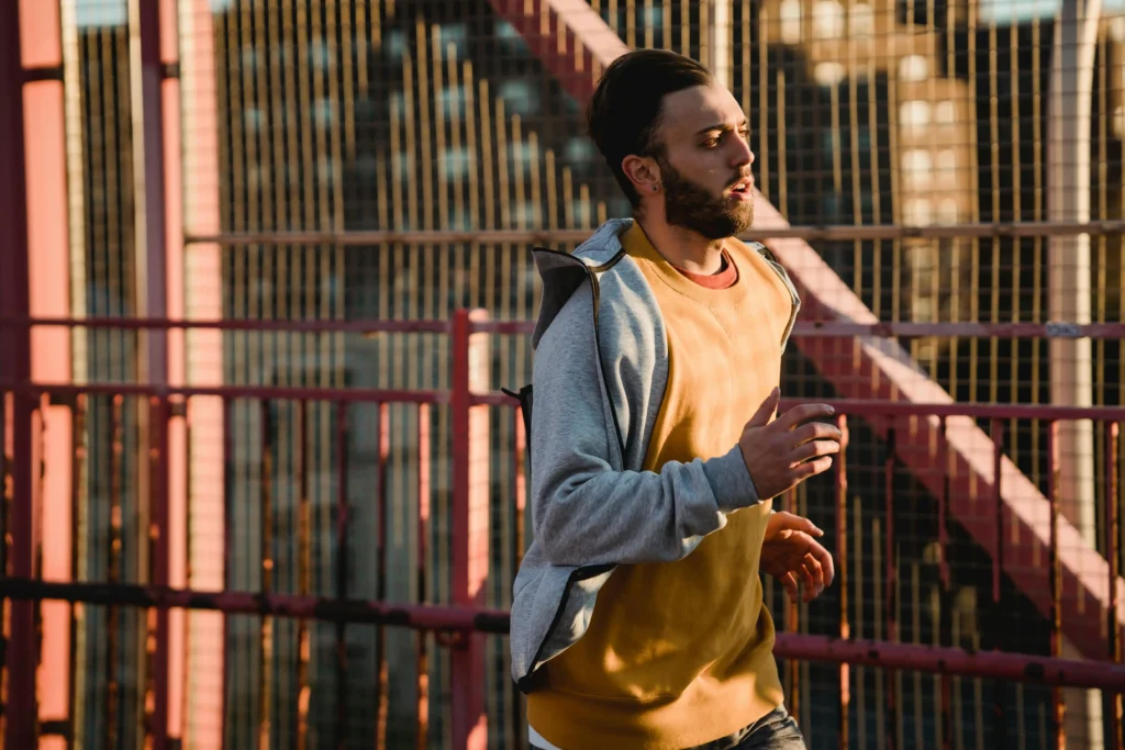 Man jogging across an urban bridge at sunset, representing an active lifestyle often associated with Hims vs Roman TRT fitness and wellness goals.