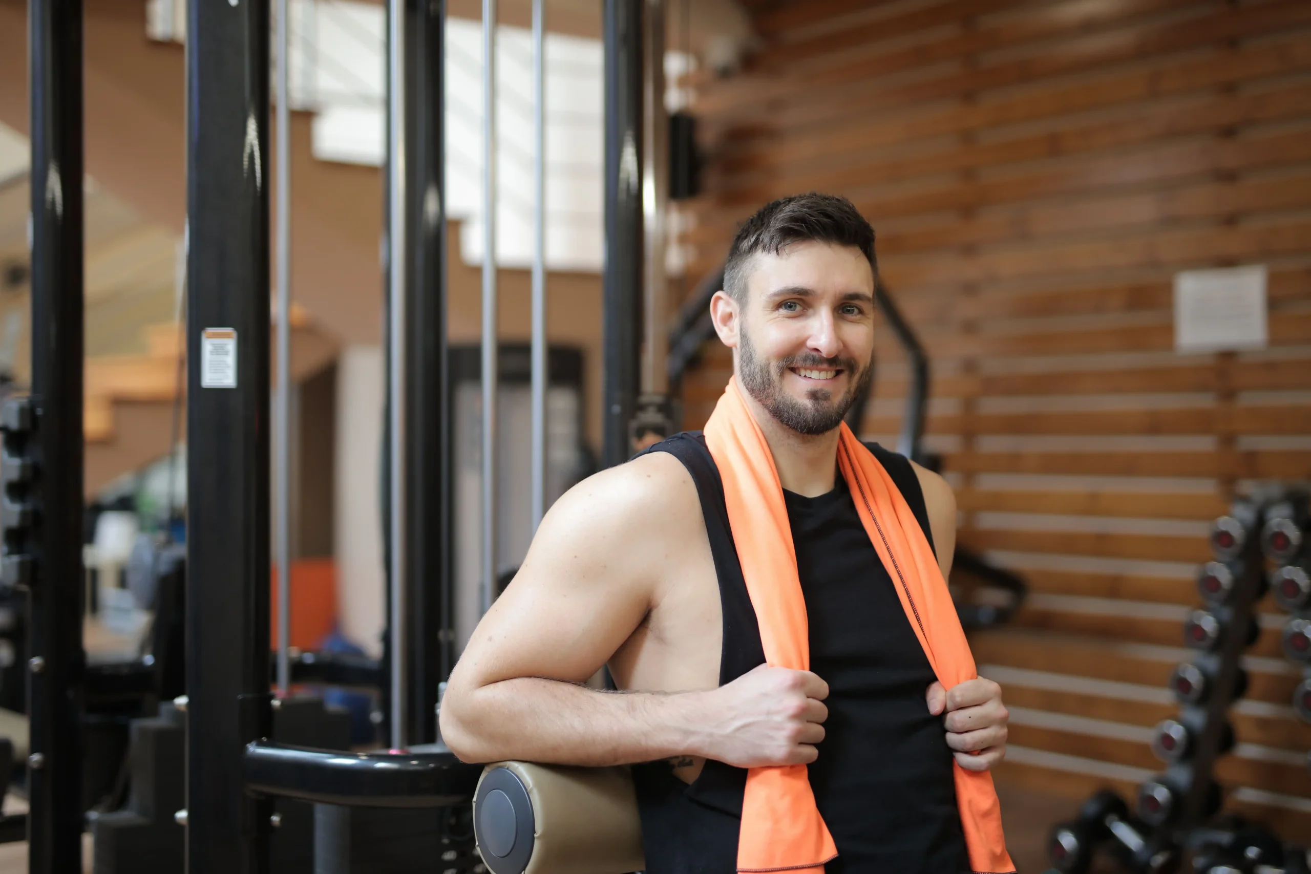 A fit man poses confidently in a gym after exercising, highlighting an active lifestyle that complements discussions about NAD therapy, energy production, and cellular health.