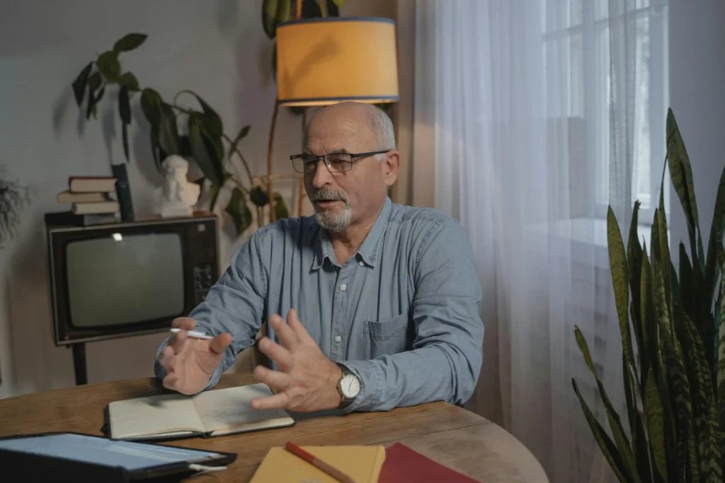 Older man participating in a virtual consultation from his home office, discussing treatment options and patient experiences in a Maximus vs TRT Nation comparison.