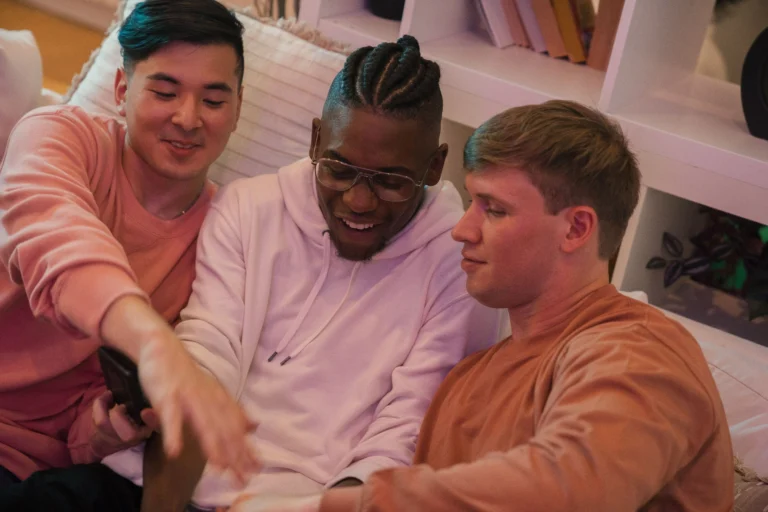 Three friends relaxing on a sofa while looking at a smartphone together, sharing opinions and experiences that reflect authentic Ro reviews and customer feedback.