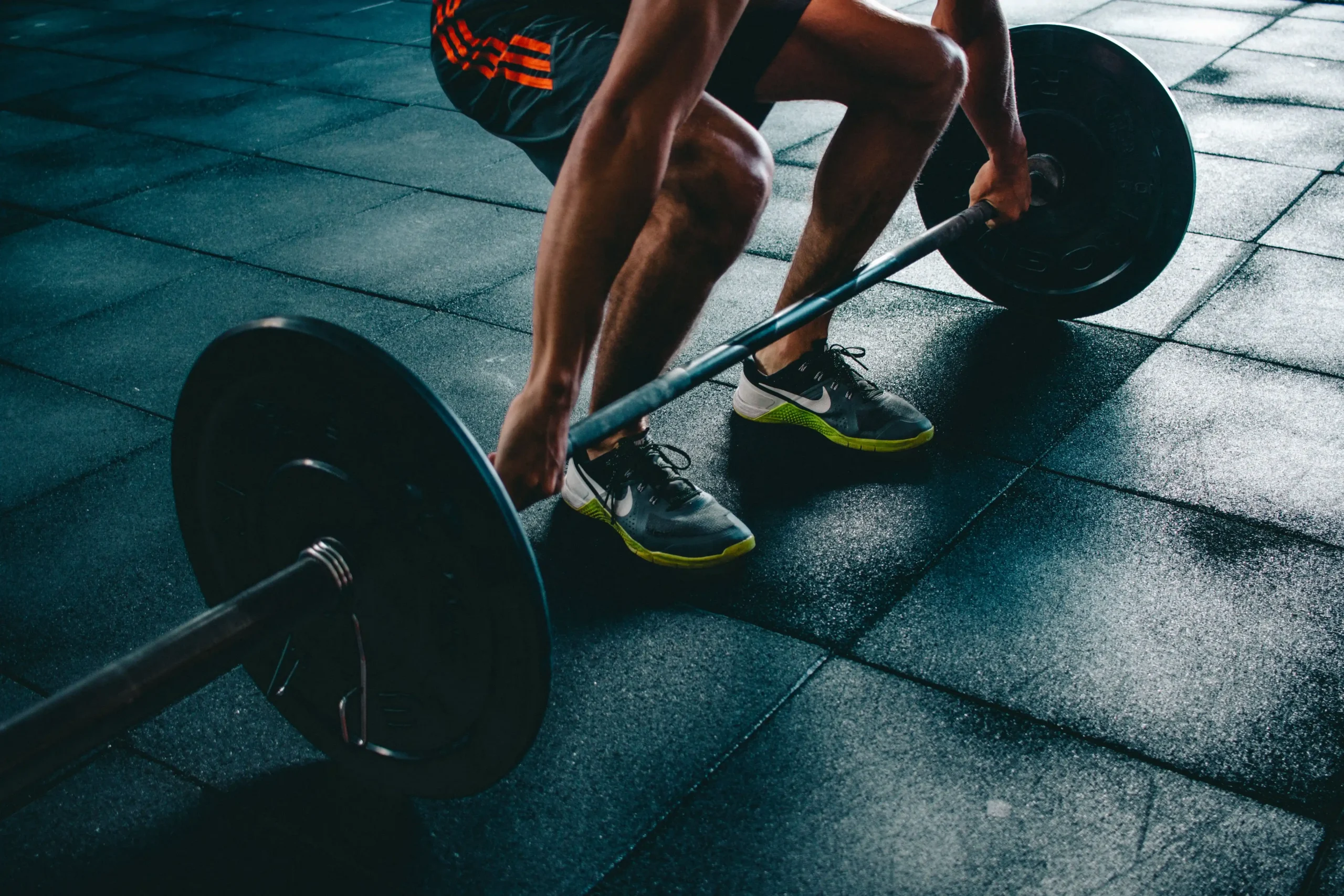 Man performing a barbell deadlift as one of the exercises to boost testosterone in a gym.
