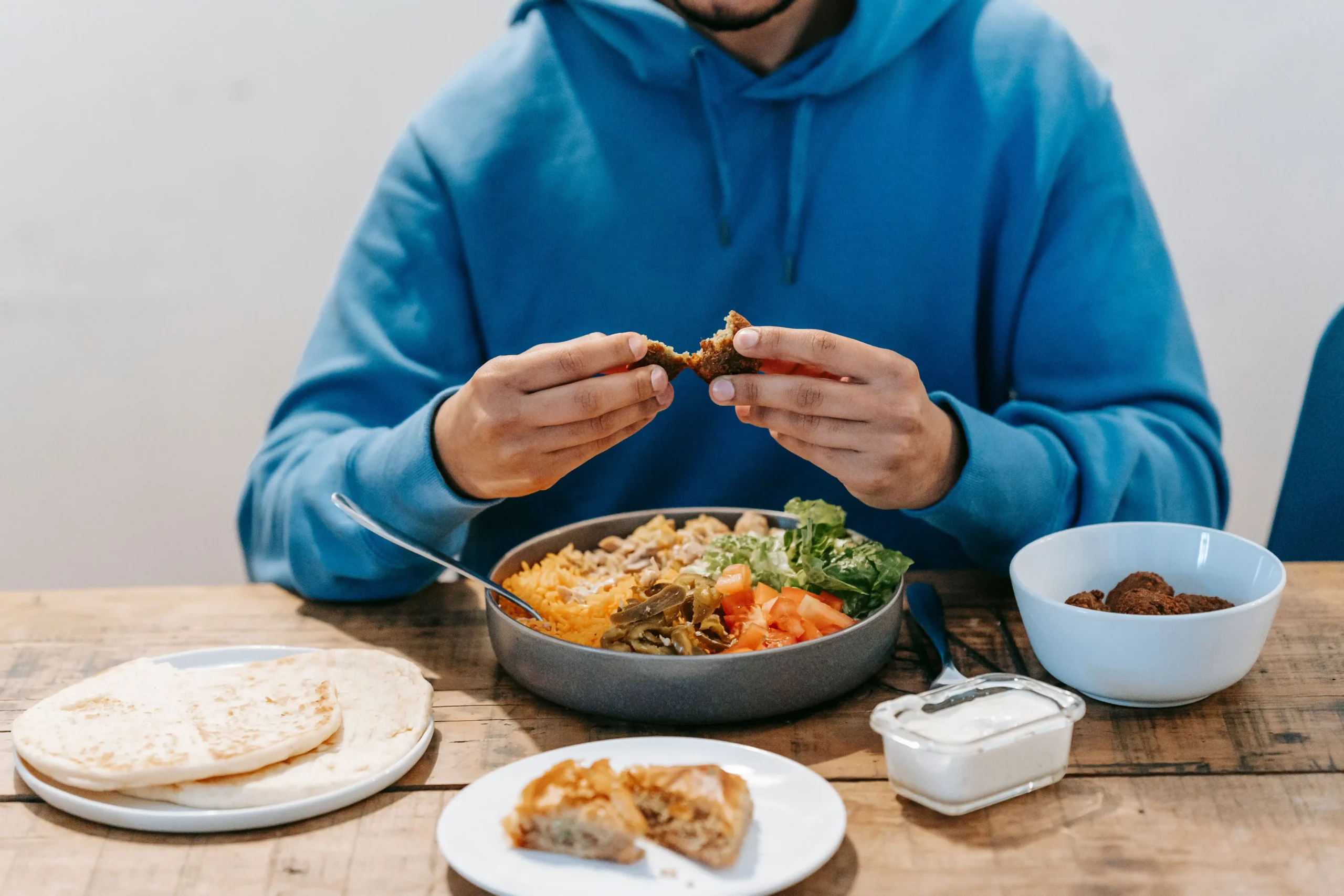 Foods that boost testosterone arranged on a table with a person enjoying a protein-rich meal.