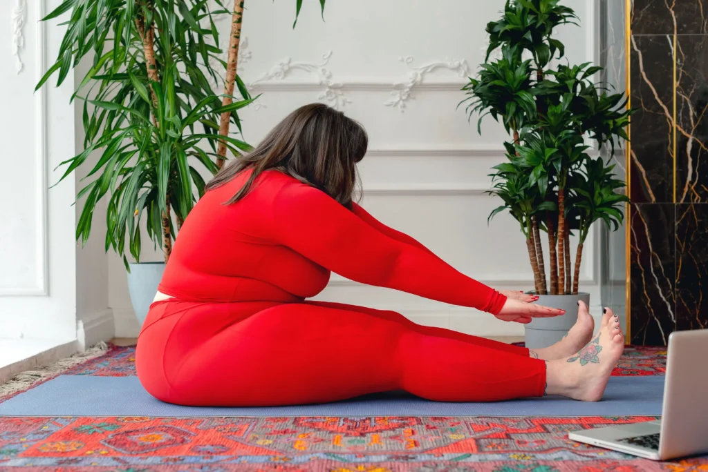 Woman stretching on an exercise mat at home as part of a wellness routine for a Henry Meds vs Roman weight loss comparison.