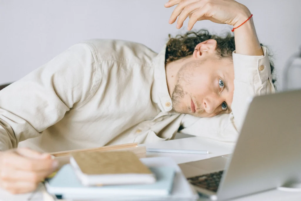 Fatigued man at a desk researching information about the low testosterone range.