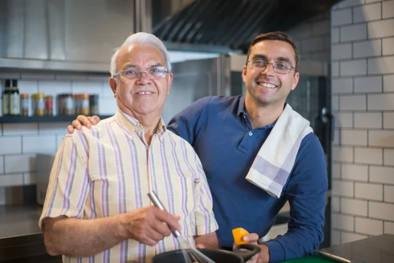Older and younger men discussing normal testosterone levels while preparing food together.