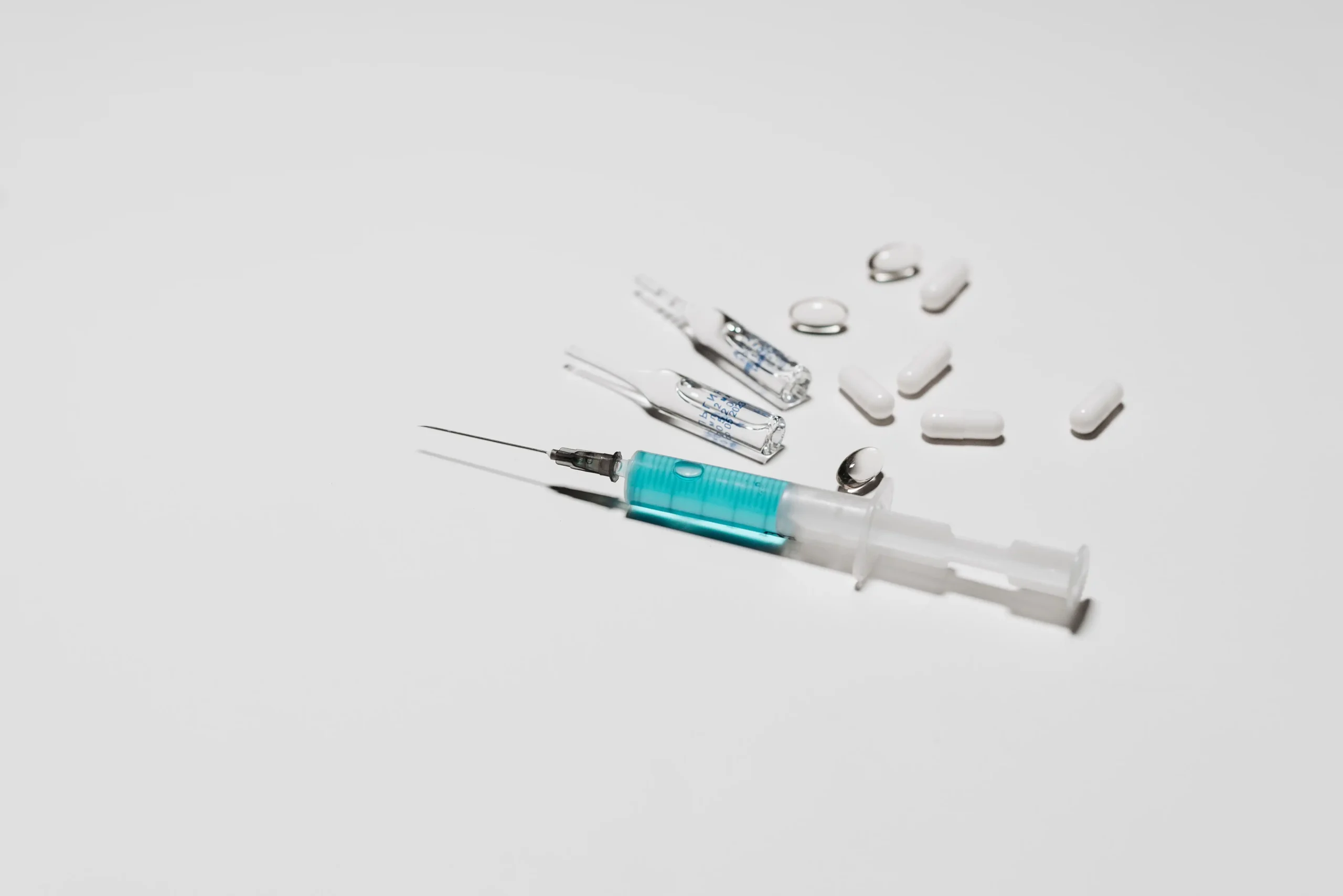 Medical syringe and medication vials representing testosterone injections vs gel treatment options.