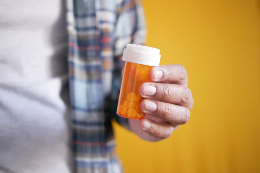 Close-up of a person holding supplements while considering a testosterone supplement review.