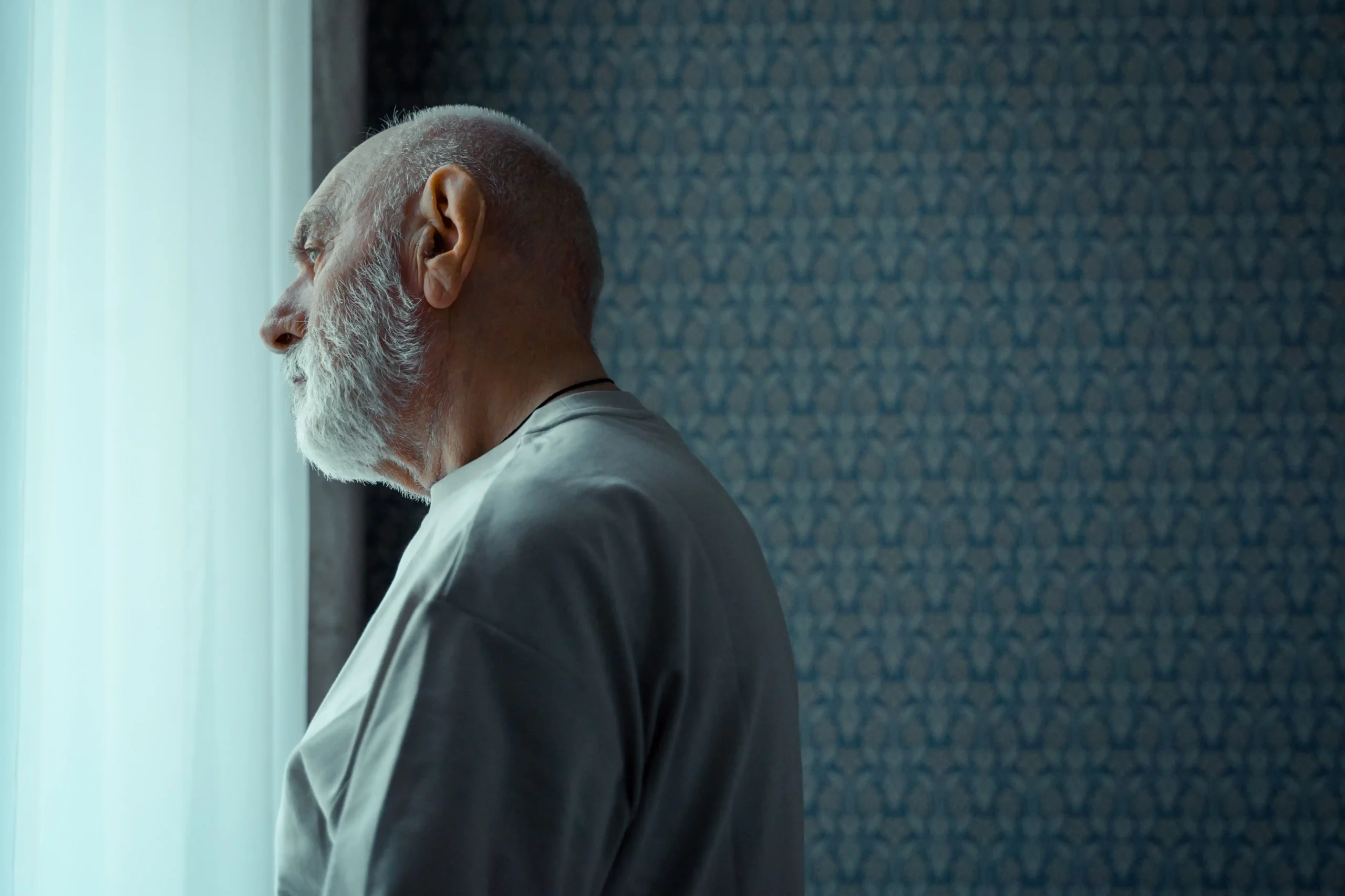 Older man standing by a window, illustrating men’s hormone health and the search for a TRT Nation coupon.