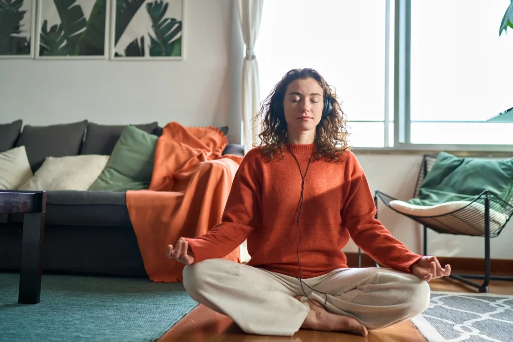 Young calm woman wearing headphones doing yoga